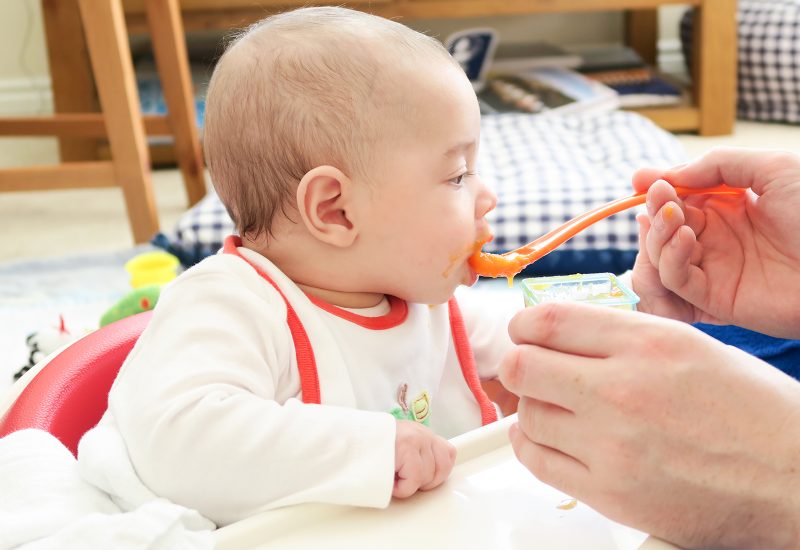 Baby eating baby food to stop baby tongue chewing