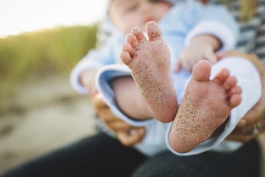 baby with sand on feet at beach
