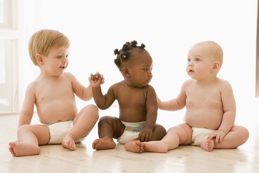 Babies sitting and holding hands in diapers