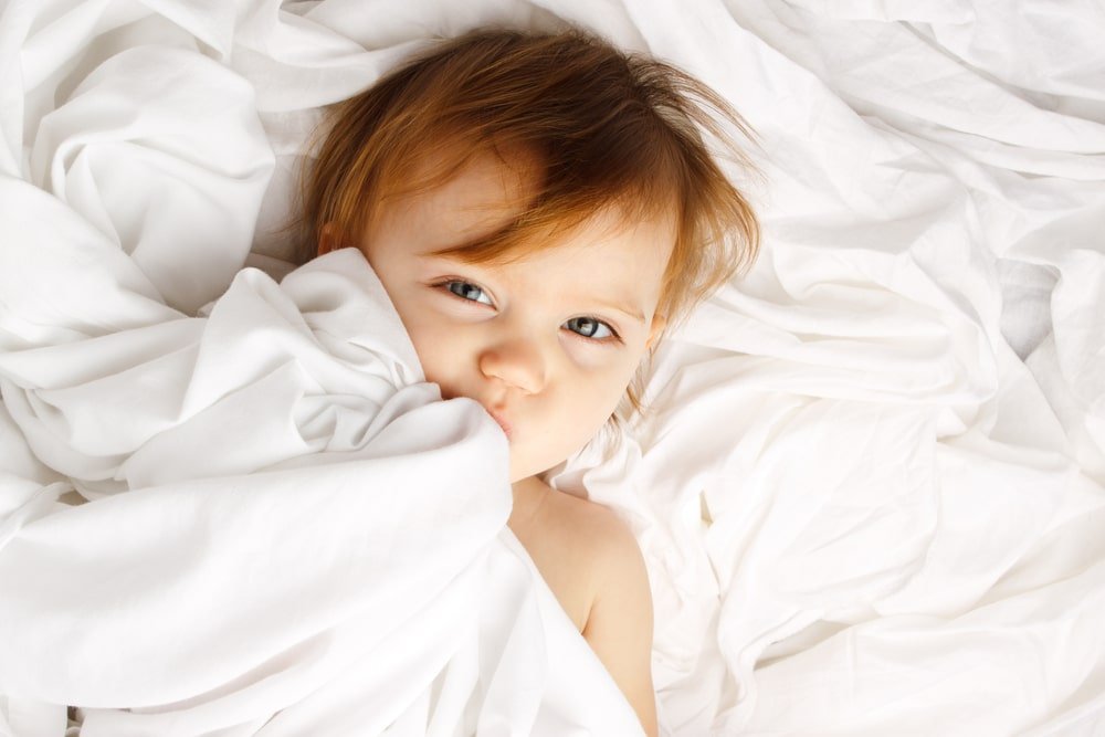 child laying on white sheet