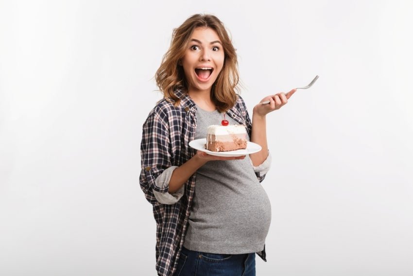 pregnant woman holding a slice of cake