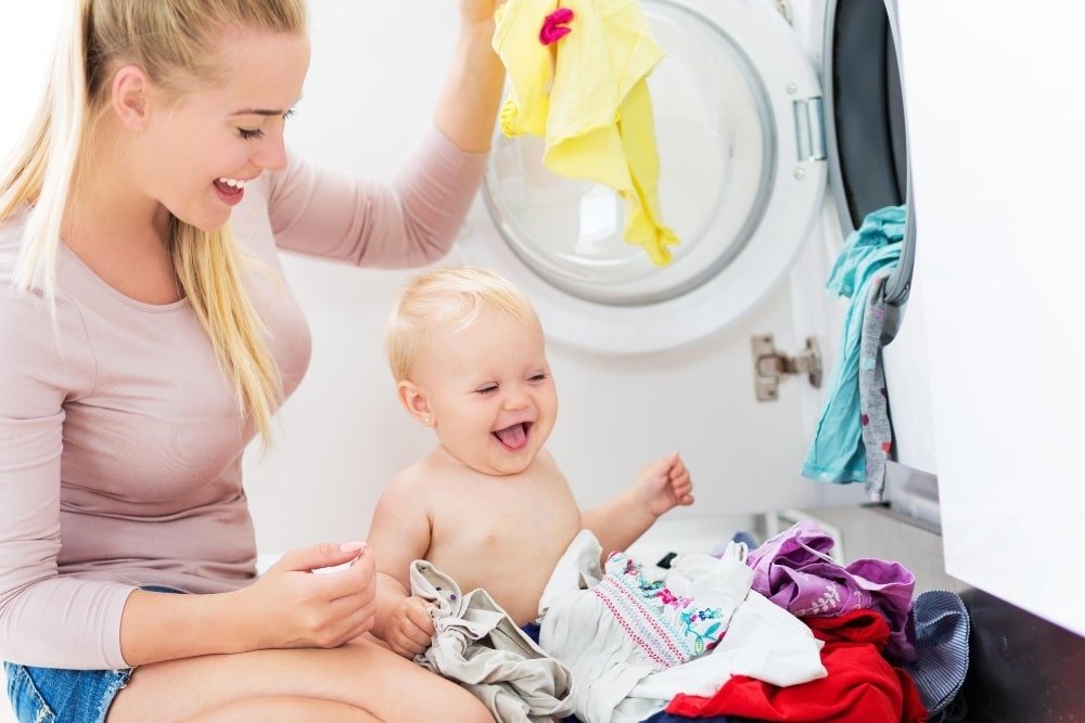 baby and mother near a washing machine