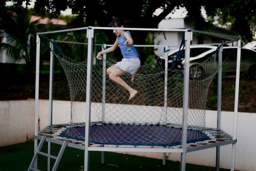 kid jumping a trampoline enclosure