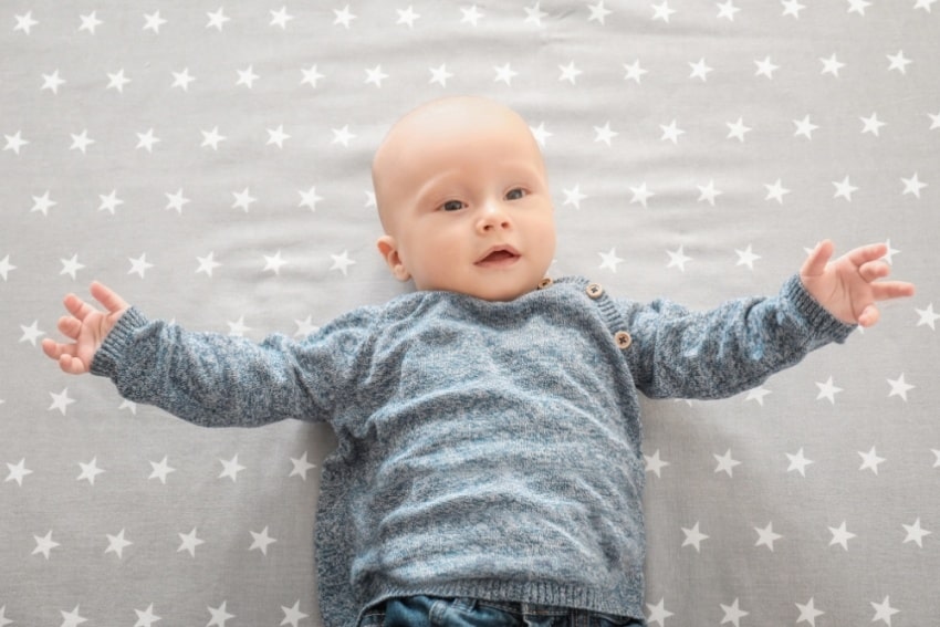 baby boy on star-patterned gray sheets