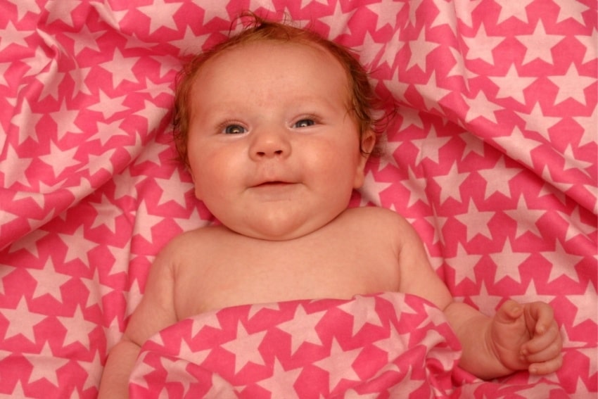 baby in pink star-patterned sheets