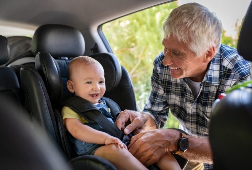 old man fastening a baby's seatbelt