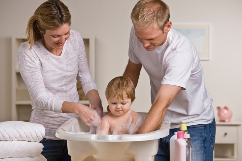 parents bathing baby