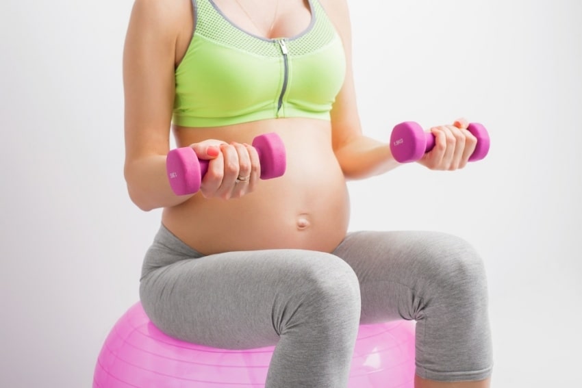 pregnant woman holding dumbells