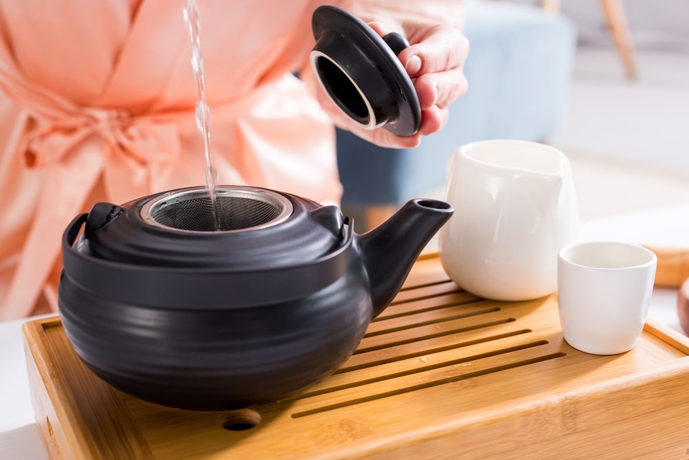 Cropped shot of woman making tea while having tea ceremony