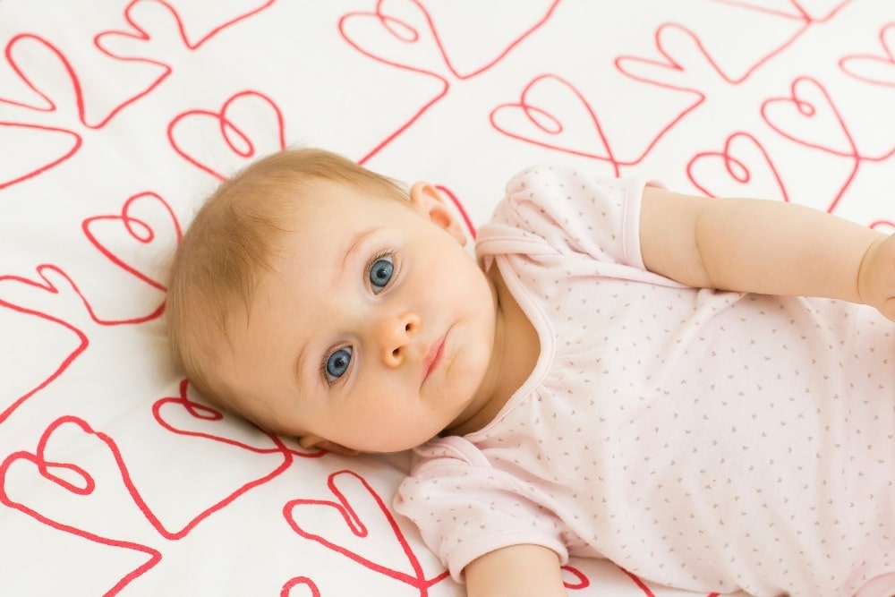 baby girl with heart shaped bed sheet