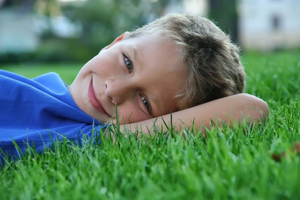 boy lying down on the grass smiling