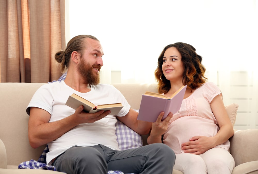 Happy beloved couple reading books waiting for birth