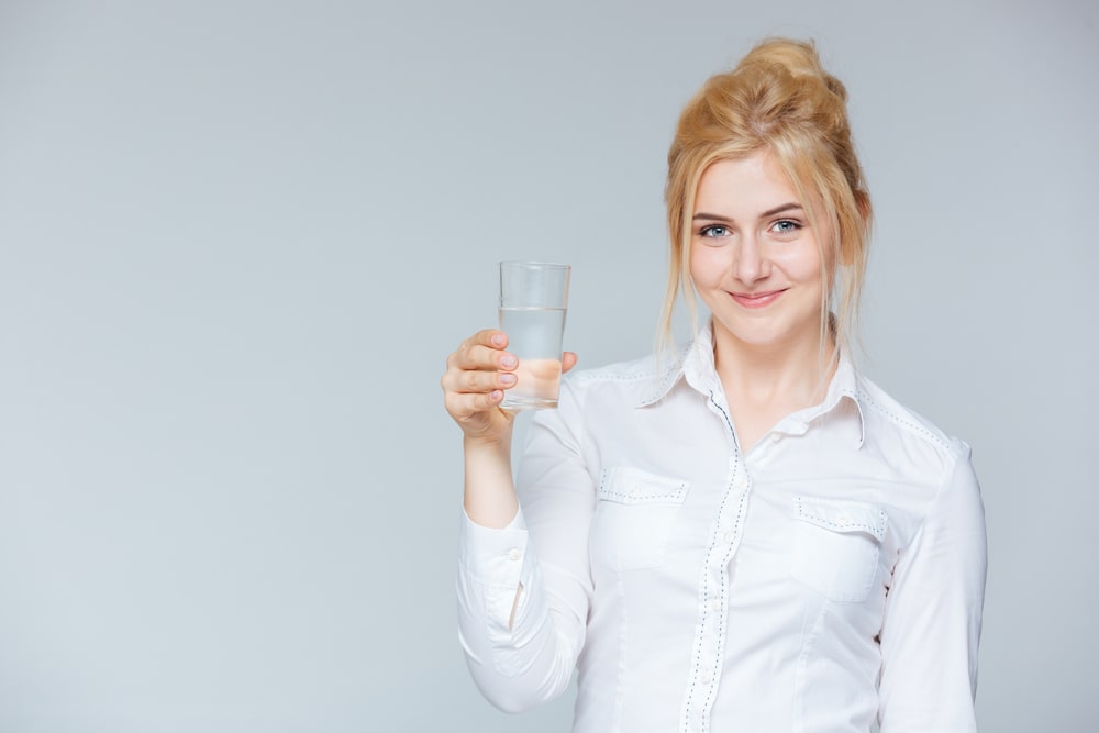 Happy lovely young businesswoman holding glass of water