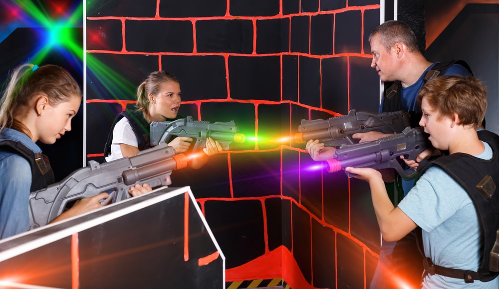 Modern young parents and children with laser pistols playing laser tag