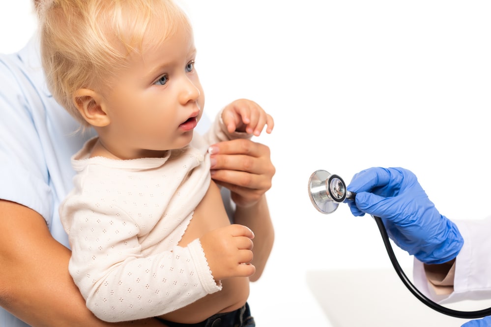 Pediatrician holding stethoscope near child