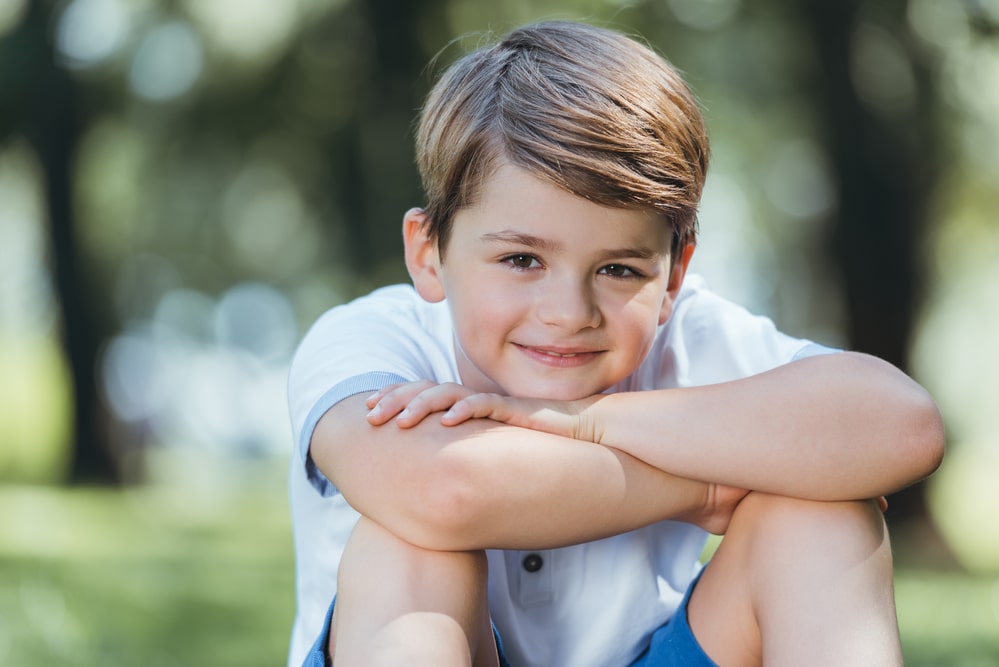 Portrait of cute happy little boy sitting and smiling at camera
