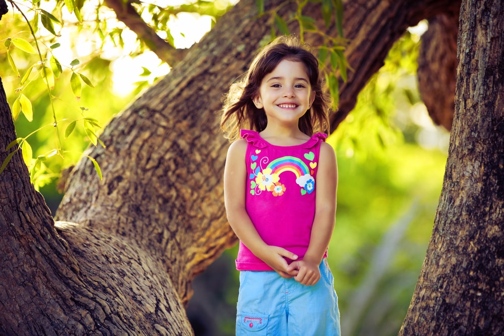 Smiling young girl standing on tree branches