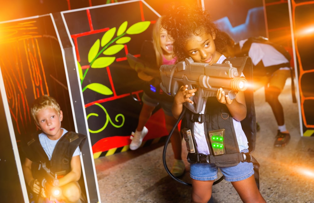 Teenager girl with laser pistol in her hands playing laser tag game