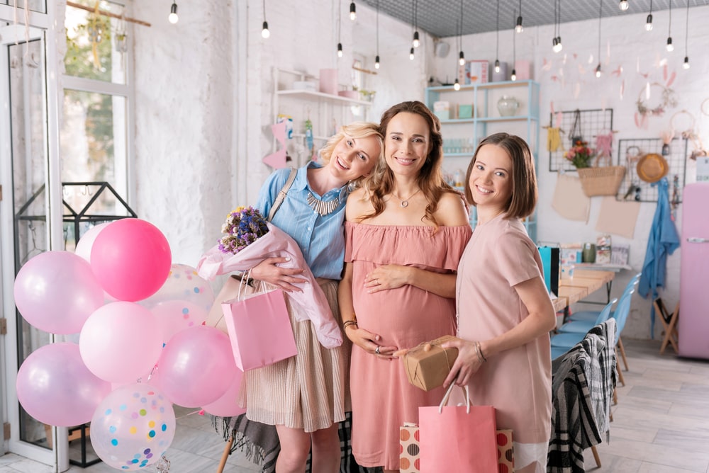 Two beautiful women standing near their pregnant sister for baby shower