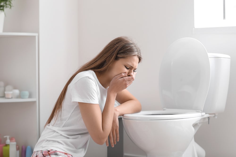 Woman leaning on open toilet seat at indoor bathroom