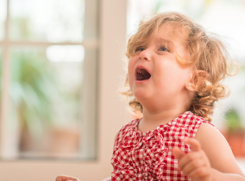 Beautiful blond child crying and shouting with tantrum at home