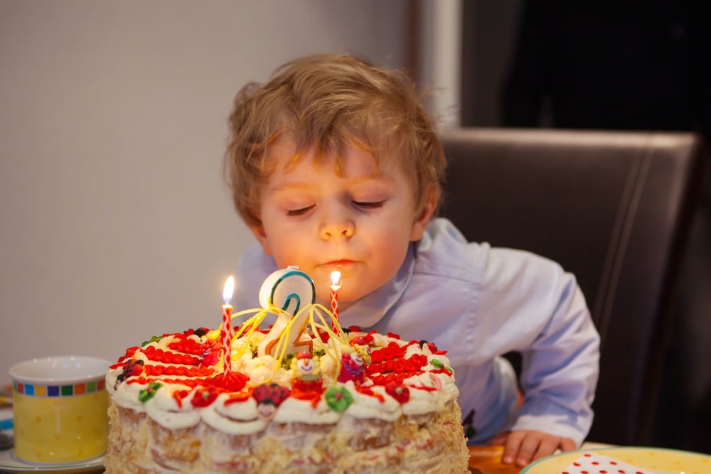 Kid celebrating birthday and blowing cake candles