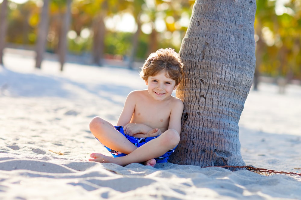 Little kid boy having fun on tropical beach