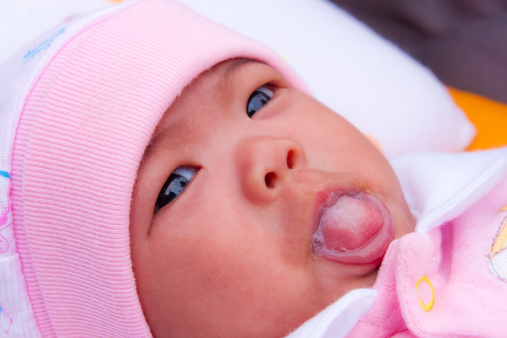 Asian newborn sticking out her tongue