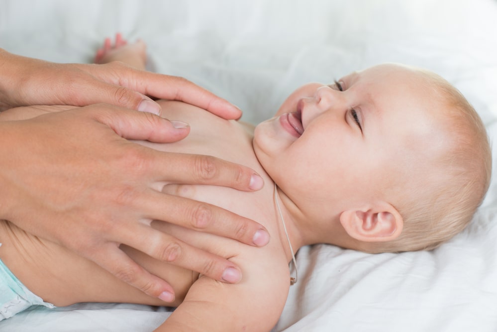 Baby massage. Mother massaging infant belly, kid laughing