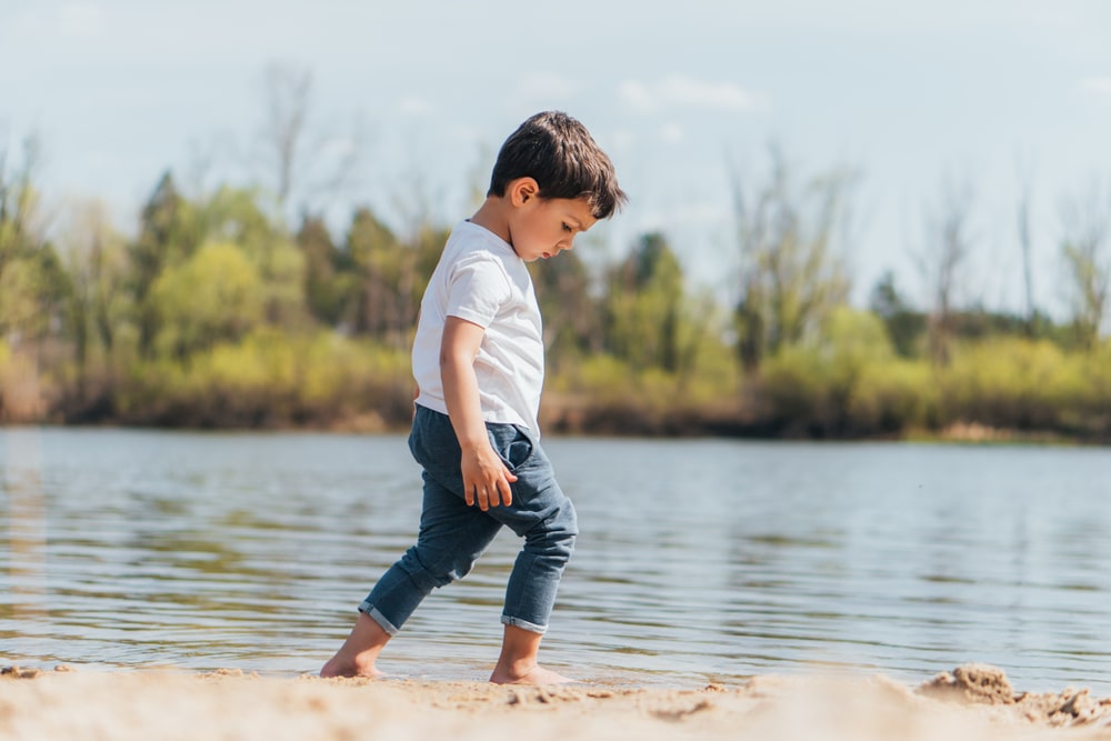 Side view of barefoot boy walking on wet sand