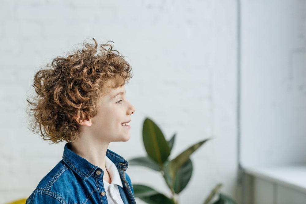 Smiling little boy with curly hair looking in window