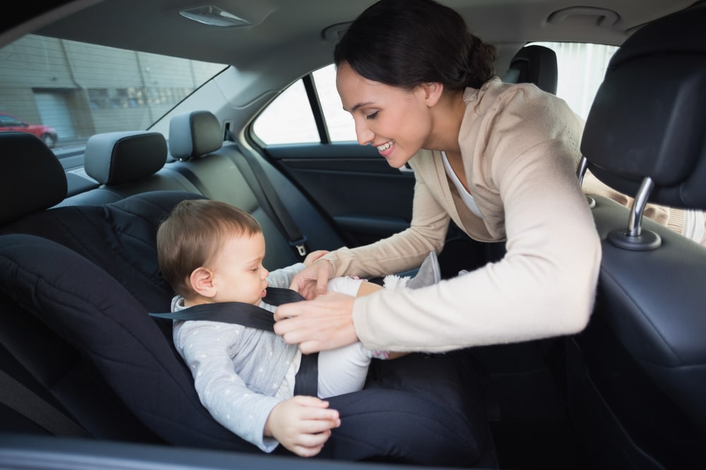 mother adjusting strap of infant car seat