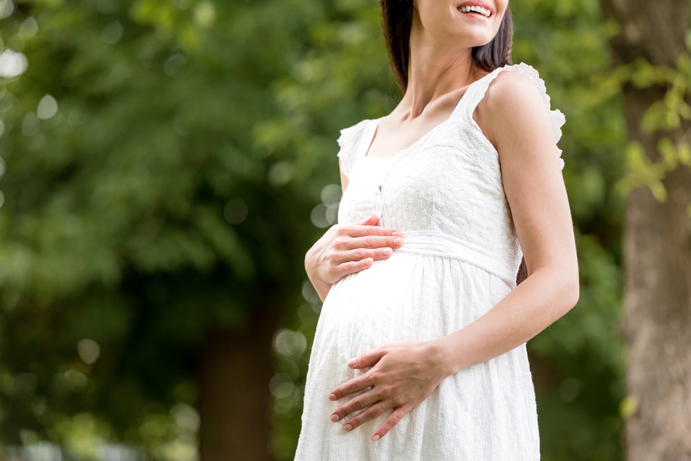 Cropped shot of smiling pregnant woman in white