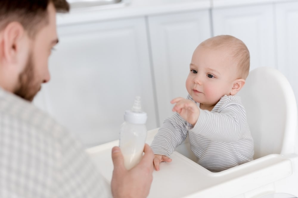baby looking at milk bottle