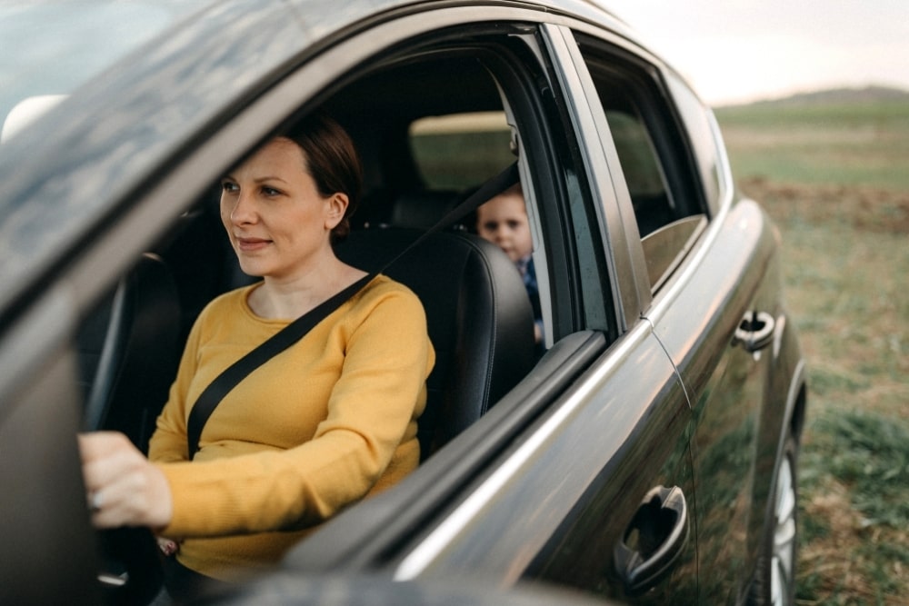 mother driving with child behind at back seat