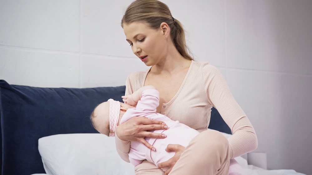 Woman holding in arms and breastfeeding baby