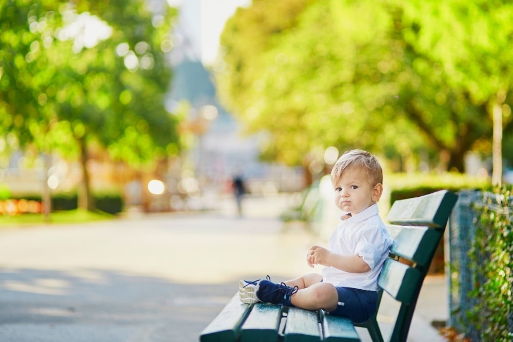little boy sitting on a bench alone