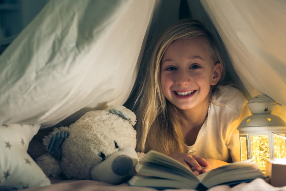 little girl smile happy reading book in bed