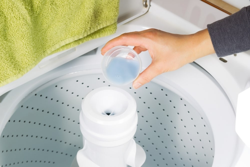 hand pouring detergent to laundry machine