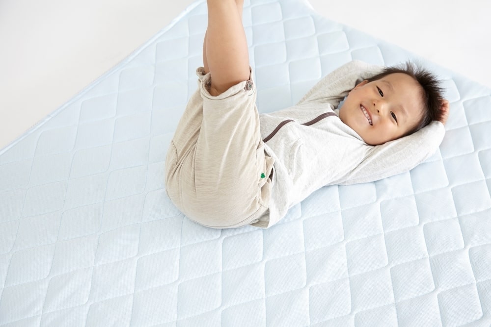 little boy happy lying down mattress-min
