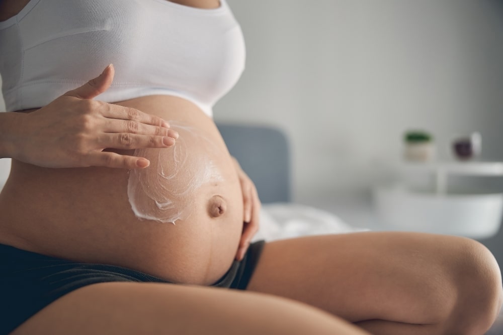 woman wiping cream on pregnant belly stretch marks1